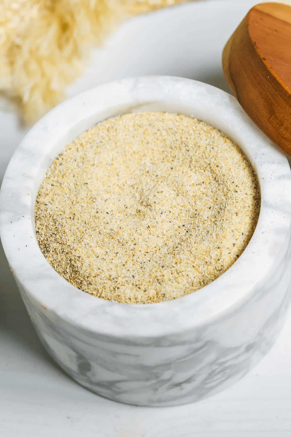 A marble container with all purpose seasoning inside.