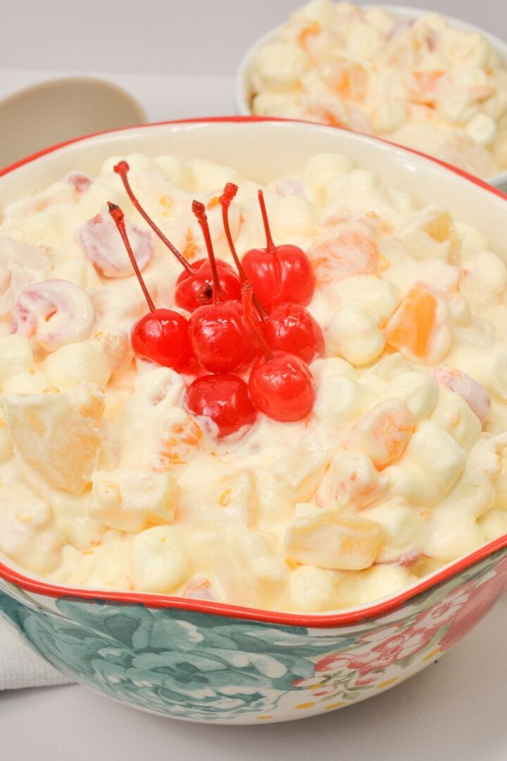Cherries on top of a fruit salad with cool whip.