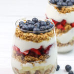 Greek Yogurt Parfait with Fruit and Granola in a clear glass cup.