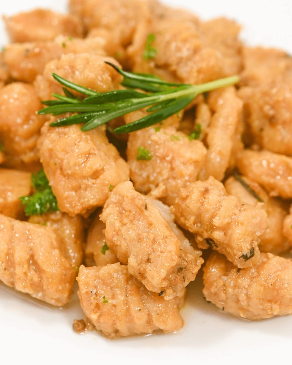 Creamy sweet potato gnocchi with a sprig of rosemary on top.